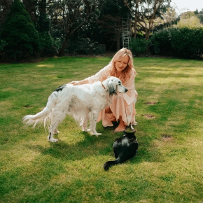 Lady crouching by a dog and cat on a green garden lawn